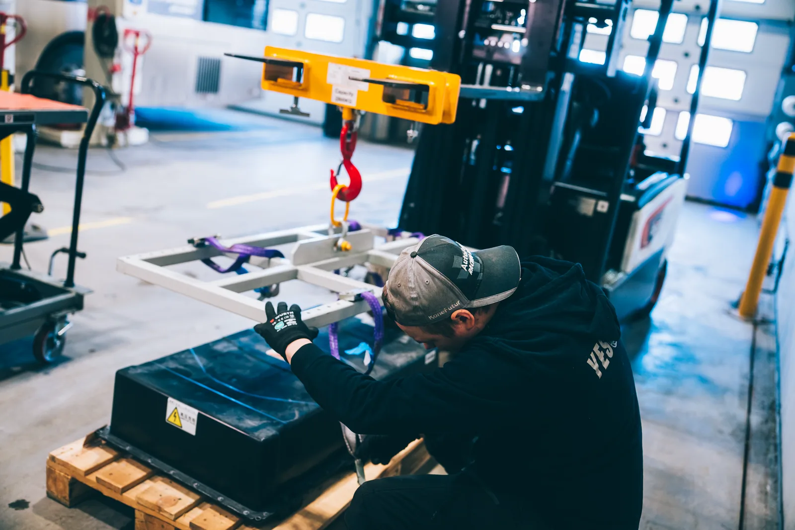 YES-EU specialist rigging a traction battery module onto a lifting frame in the workshop